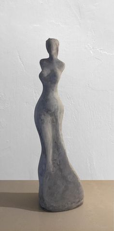 a gray sculpture sitting on top of a table next to a white wall and floor