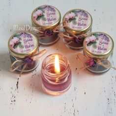 four small jars filled with candles sitting on top of a table