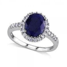 an oval shaped blue sapphire and diamond halo engagement ring in white gold with diamonds around it