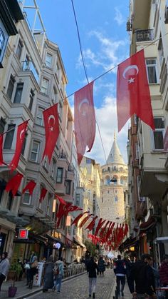 people walking down a street with flags hanging from buildings