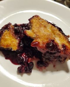 a piece of cake on a plate with blueberry compote in the middle