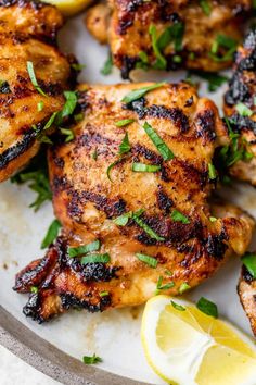 grilled chicken with lemon wedges and herbs on a platter, ready to be eaten