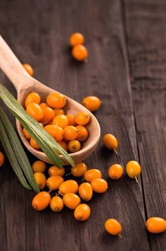 a wooden spoon filled with yellow berries on top of a table