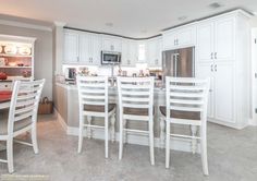 a kitchen filled with white cabinets and chairs next to a dining room table in front of an oven