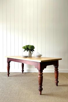 a wooden table sitting on top of a carpeted floor next to a white wall