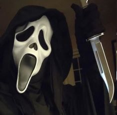 a person wearing a ghost mask and holding a knife in their hand with both hands