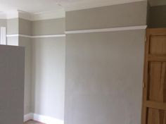 an empty room with white walls and wood doors in the corner is painted light gray