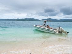 a small boat in the water with two people on it's back and one person sitting inside