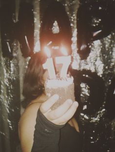 a woman holding a lit candle in front of her face