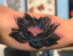 a black and blue flower tattoo on the arm