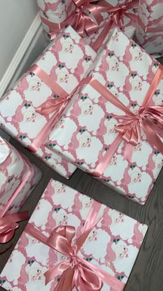 several wrapped presents are sitting on the floor next to each other with pink ribbons and bows