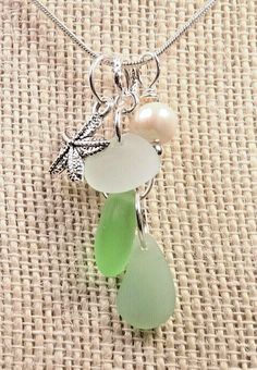 three sea glass necklaces hanging from a silver chain on a burlock cloth