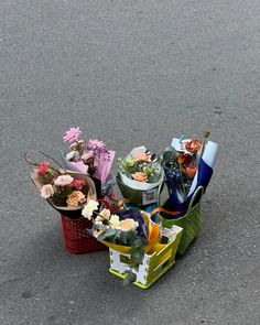 two baskets filled with flowers sitting on the side of a road next to each other