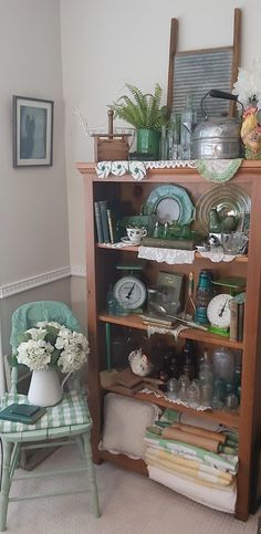 a wooden bookcase filled with lots of books next to a green and white chair