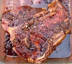 a piece of meat sitting on top of a pan covered in sauce and seasoning