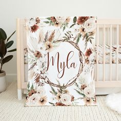 a baby crib with a flowered blanket on it and the name mya