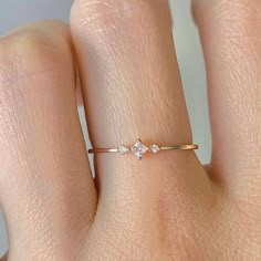 a woman's hand wearing a gold ring with three small diamonds on the band