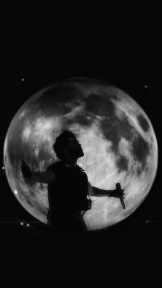 a person standing in front of the moon with their arms outstretched and hands out to each other