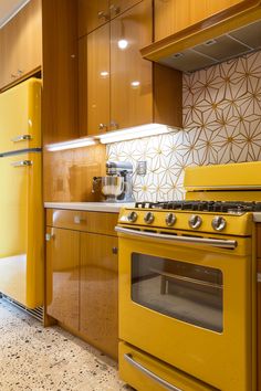 a yellow stove top oven sitting inside of a kitchen next to wooden cupboards and counter tops