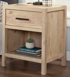 a wooden nightstand with books and a potted plant sitting on top of the shelf