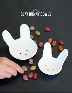 two white bowls with bunny faces on them and beans in the bottom one bowl is filled with jelly beans