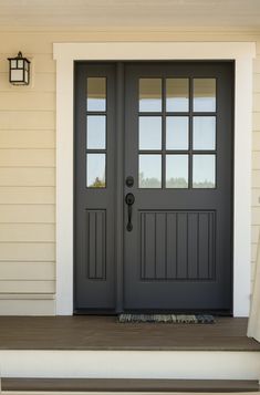 a black front door with two sidelights and a bench on the outside steps next to it