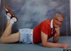 an older man laying on the ground with his feet up in front of him, wearing shorts and a red shirt