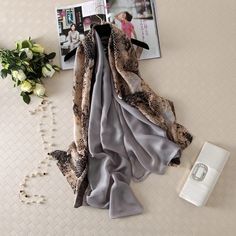 Elevate your style with our Silky Satin Oblong Scarf. Each scarf is carefully chosen to add elegance and sophistication to your everyday attire and special events. Made from premium silky satin, this scarf is lightweight, soft, and boasts a subtle shine for a glamorous touch. With a variety of beautiful designs, chic patterns, and stunning colors, each scarf is a work of art. Whether it's keeping you warm and cozy in the winter or cool and stylish in the summer, this long oblong scarf is the per Poncho Winter, Winter Cape, Beach Shawl, Silk Scarf Style, Silk Scarf Wrap, Chiffon Hijab, Pure Silk Scarf, Luxury Scarves, Scarf Women Fashion