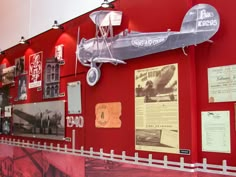 an airplane on display in a museum with red walls and white picket fence around it