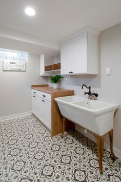 an empty kitchen with white cabinets and black and white floor tiles on the floor, along with a sink