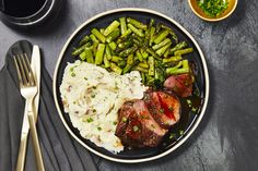 steak, mashed potatoes and broccoli on a plate with goldware next to it