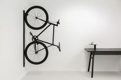 a bike mounted to the side of a white wall next to a table and chair