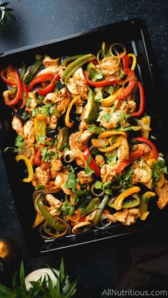 chicken fajita with peppers and cilantro in a black tray on a table