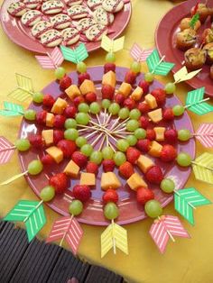 a table topped with pink plates filled with fruit and pastries next to other desserts