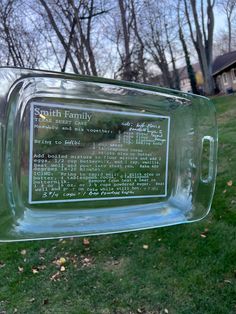 a glass bottle with a plaque on it sitting in the grass next to some trees