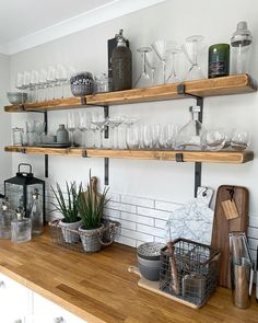 the shelves are filled with glasses and other kitchen items on wooden countertops in front of white brick walls