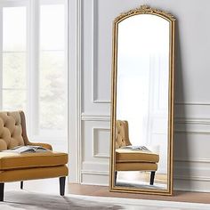 a large mirror sitting on top of a wooden floor next to a chair and ottoman