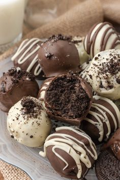 chocolate covered cookies and oreos on a plate with a glass of milk in the background