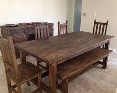 a wooden table and chairs in a room with tile flooring, white walls and wood furniture