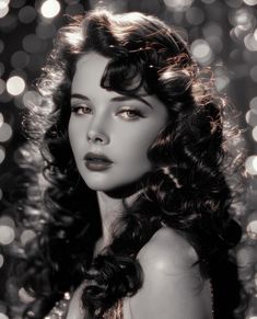 a black and white photo of a woman with long curly hair, wearing a sparky dress