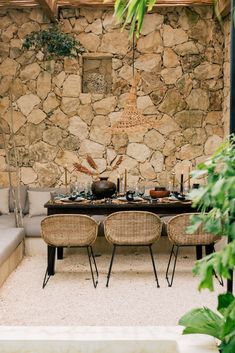 an outdoor dining area with wicker chairs and table set up for four, surrounded by stone walls