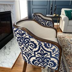 two chairs sitting in front of a fireplace with blue and white designs on it's armrests