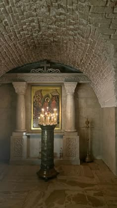 a candle is lit in the middle of a room with paintings on the wall behind it