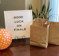 two brown bags sitting on top of a table next to a sign that says good luck on final's