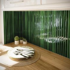 a table with plates and utensils on it in front of a green wall