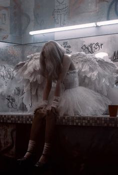 a woman sitting on top of a counter covered in white feathers