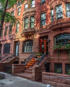 an old brick building with many windows and steps leading up to the front door, surrounded by greenery