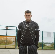 a man standing in front of a basketball hoop wearing black and white pinstripe tracksuits