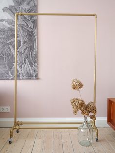 a vase filled with flowers sitting on top of a wooden floor next to a pink wall