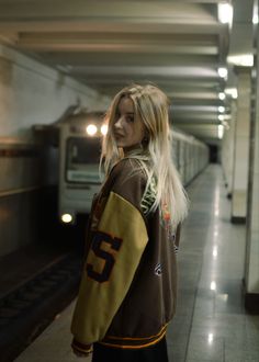 a woman standing in a subway station next to a train